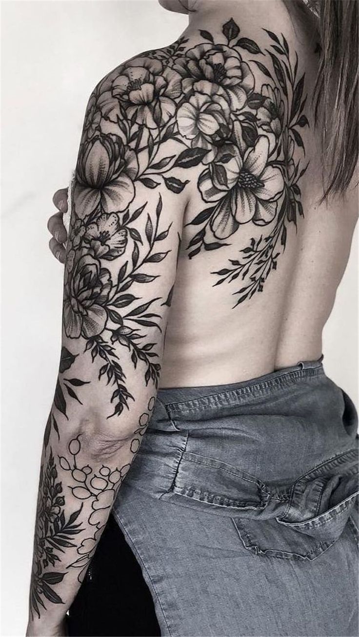 a woman's back with flowers on her arm and shoulder, in black ink