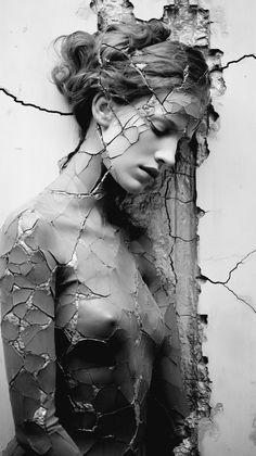 black and white photograph of a woman with wire on her head, in front of a cracked wall