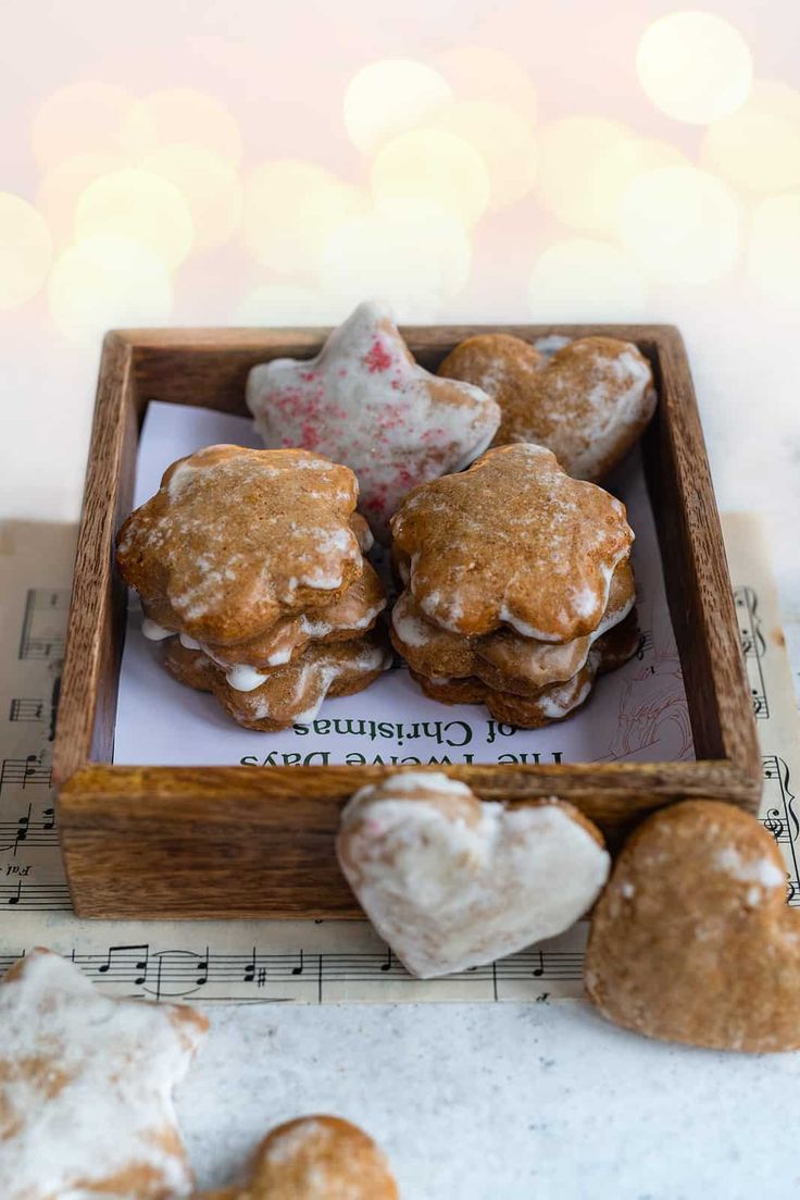 heart shaped cookies in a wooden box on top of sheet music with christmas lights in the background