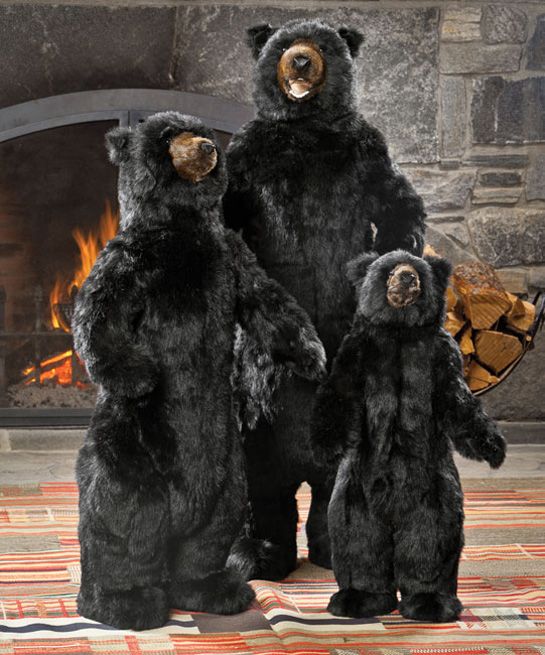 three black bears standing next to each other in front of a fire place and fireplace