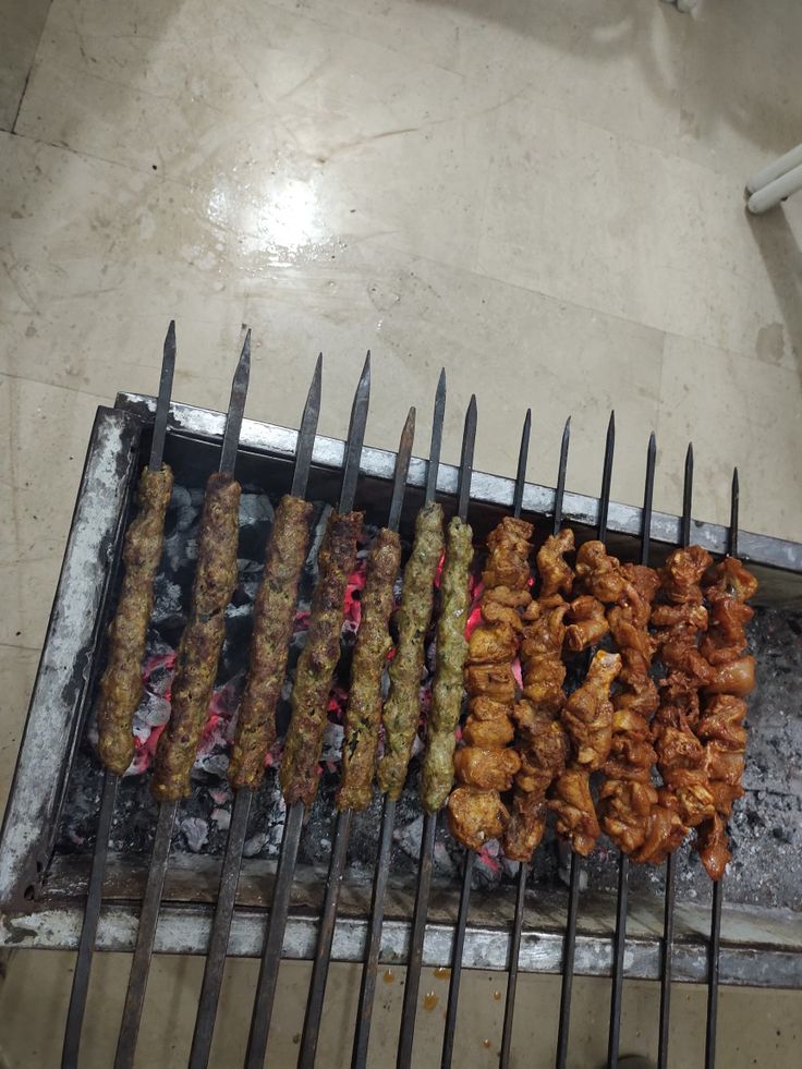 several skewers of food cooking on an outdoor grill