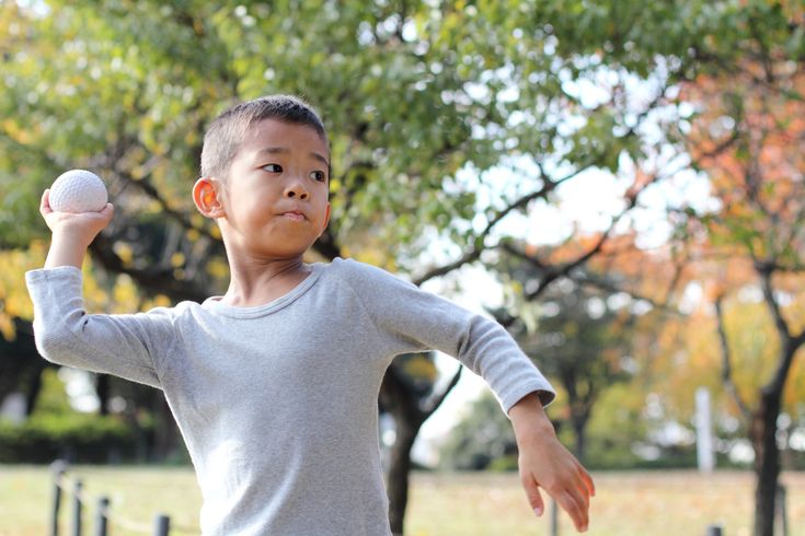 a young boy throwing a ball in the park