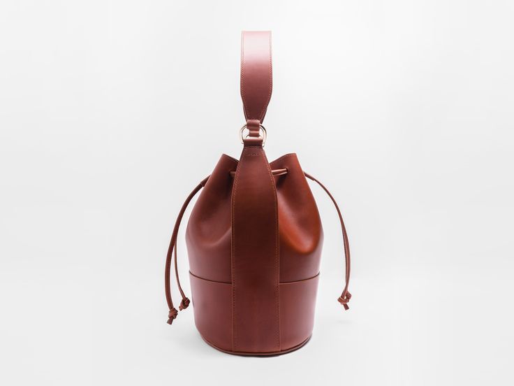 Our interpretation of a classic-- the bucket bag. Utilitarian, minimal, still sophisticated and beautiful. In our beloved Buttero leather from Italy. Balloon shaped body for rich, soft pleats when the drawstrings are pulled tight. Roomy interior to carry all your necessities.Featuring a handle along with a detachable shoulder strap, easily making this an everyday, carry-all bag. Gold finish brass hardware. Lined interior. Made with the finest, full grain Italian vegetable tanned leather. This le Timeless Everyday Bucket Bag, Timeless Bucket Bag For Daily Use, Timeless Travel Bucket Bag, Formal Bucket Bag With Removable Pouch, Timeless Evening Bucket Bag, Modern Pouch Bucket Bag For Formal Occasions, Cognac Bucket Bag For Evening, Modern Formal Pouch Bucket Bag, Modern Formal Bucket Bag Pouch Style