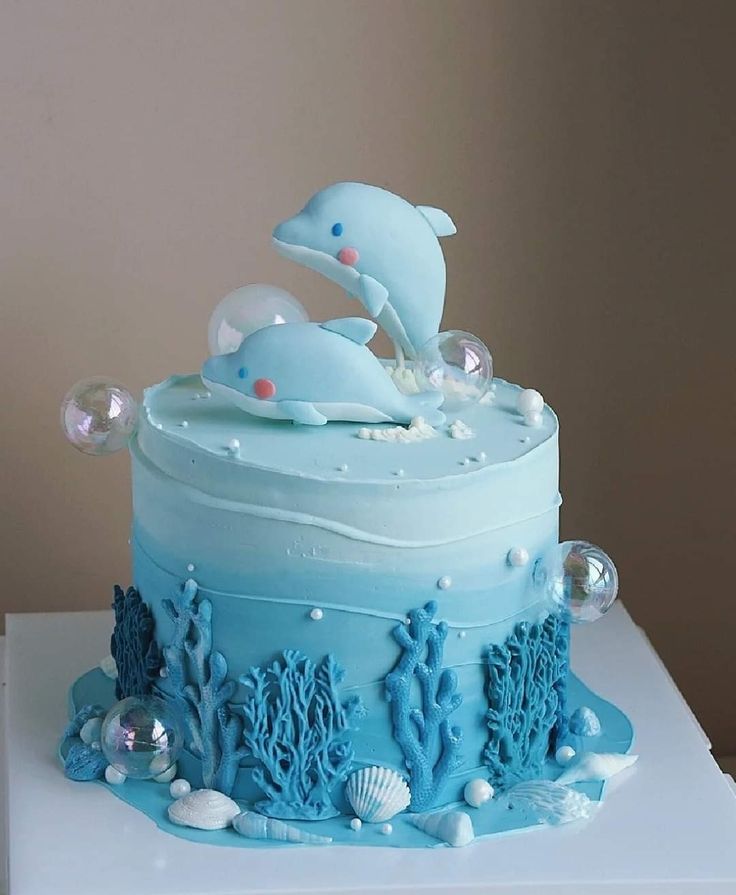 a blue cake decorated with dolphins and seashells