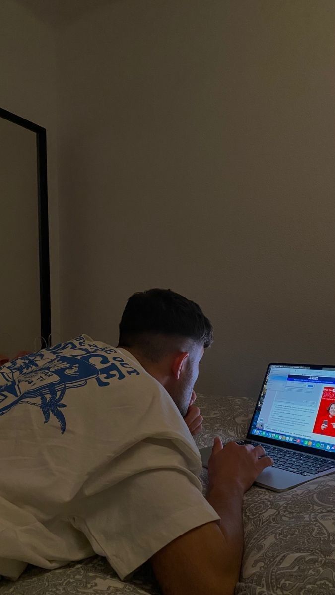 a man laying in bed with his laptop on his lap and looking at the screen