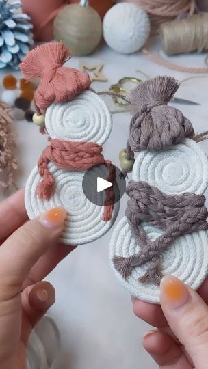 two hands are holding small pieces of yarn