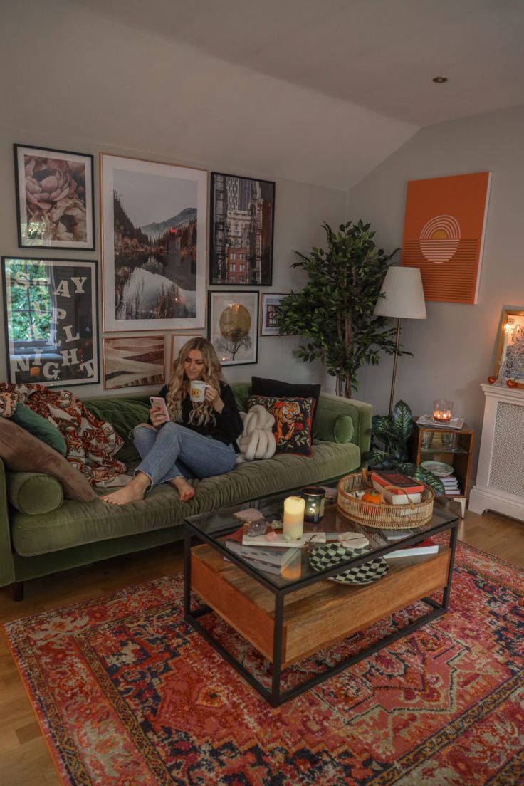 a woman sitting on top of a green couch in a living room next to a coffee table