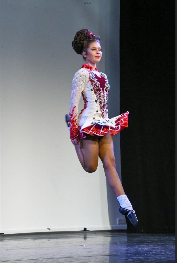 a woman in a red and white dress is dancing