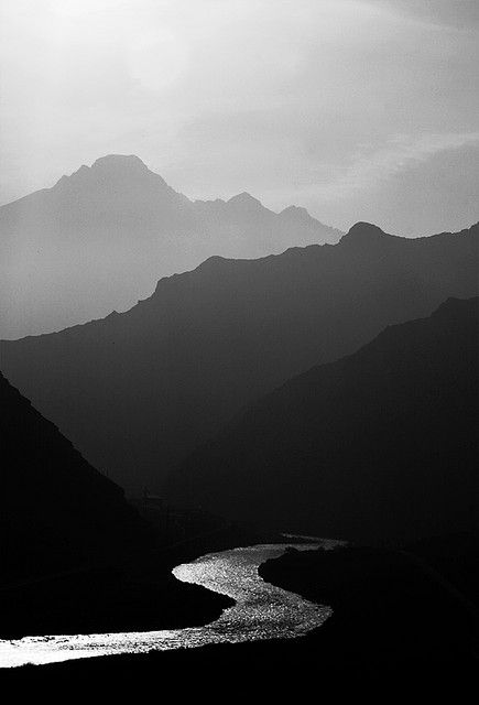 black and white photograph of mountains with river in foreground