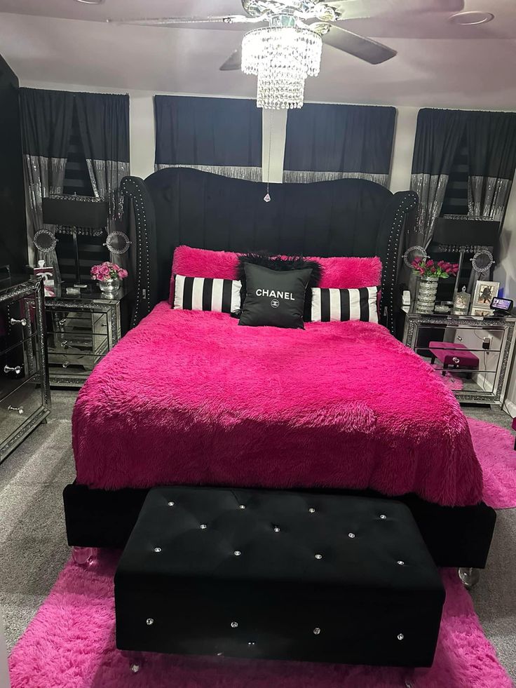 a black and white bedroom with fuchsia pink bedding, chandelier and mirrored furniture