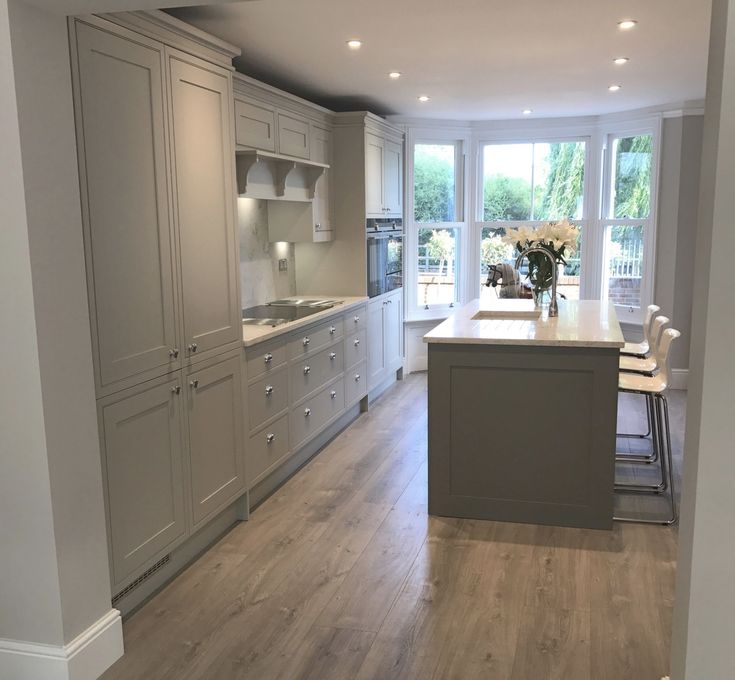 a large kitchen with white cabinets and wood flooring is seen from the doorway to the dining room