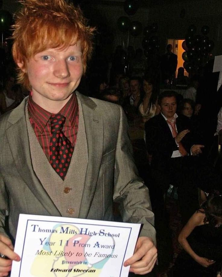 a young man in a suit and tie holding up a sign