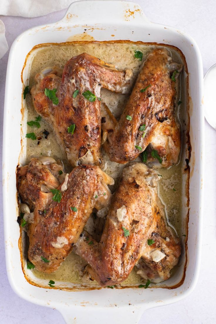 chicken in a white casserole dish with green garnish