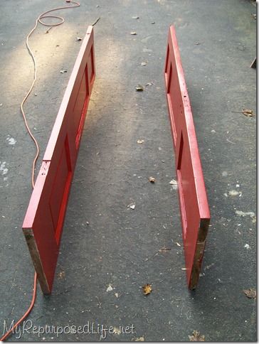 two red wooden benches sitting on top of a cement floor next to a power cord