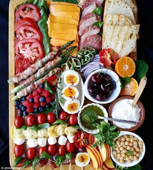 a wooden platter filled with meats, cheeses and fruit on top of it