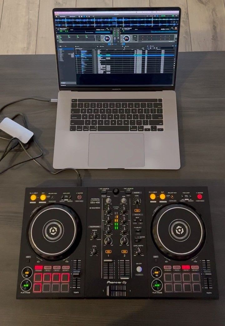 a laptop computer sitting on top of a wooden table next to a dj's controller