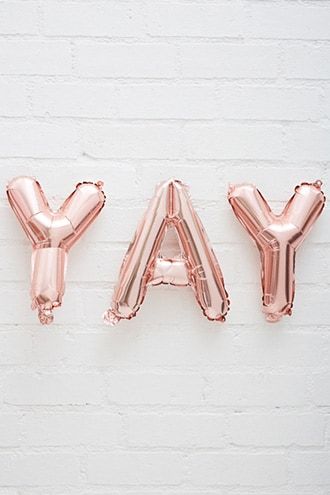 balloons spelling out the word may on a white brick wall