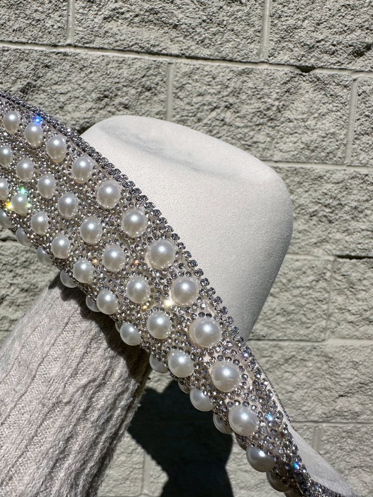 This Perla Rhinestone/Pearl Western Hat is the perfect accessory for the Rodeo & Festival Season or any special event. The white hat features exquisite rhinestones and pearls, adding a touch of glamour to any outfit. Elevate your western look and stand out from the crowd with this stunning hat. Rhinestone & Pearl Detail White Interior Drawstrings For Adjustable Sizing Faux-Suede Thank You For Shopping At Berenis! All Western Hat Sales Are Final! White Western Hats, Rhinestone Hat, Rodeo Time, Western Hat, Western Look, Western Hats, Cowgirl Hats, White Hat, Love Style