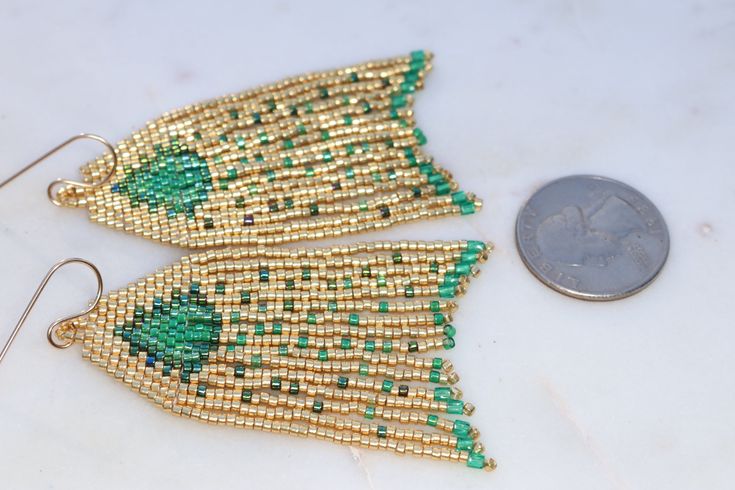 Handmade artisan boho chandelier earrings in the most gorgeous shades of emerald green and gold with gently swaying fringe. Each tiny bead is selected and hand sewn into place, one at a time with a needle and thread. No plastics, no glue, no looms - completely hand stitched with strong nylon thread.Ear wires are gold filled.Lightweight and comfortable, these earrings make a great gift or stocking stuffer for that special woman or a treat for yourself. All our items ship boxed and ready to gift. Emerald Green And Gold, Boho Chandelier, Fall For You, Handmade Artisan, Needle And Thread, Stocking Stuffer, Chandelier Earrings, Hand Stitched, Ear Wires