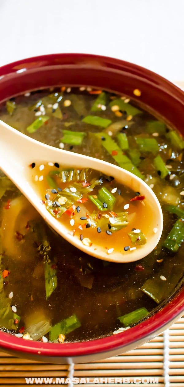 a red bowl filled with broccoli soup and a spoon