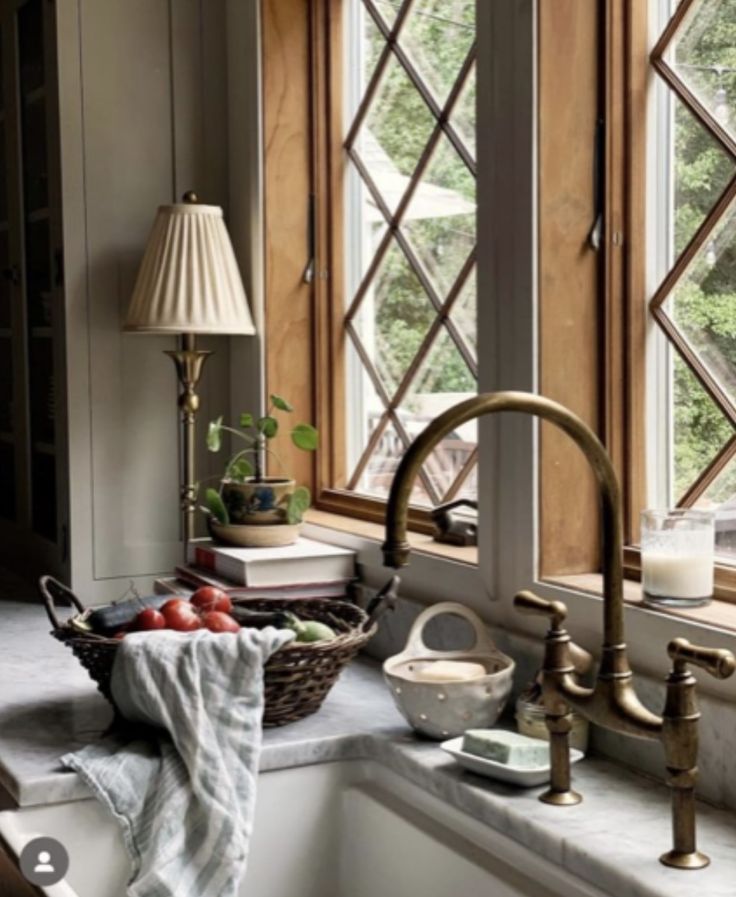 a kitchen sink sitting under a window next to a basket filled with fruits and vegetables