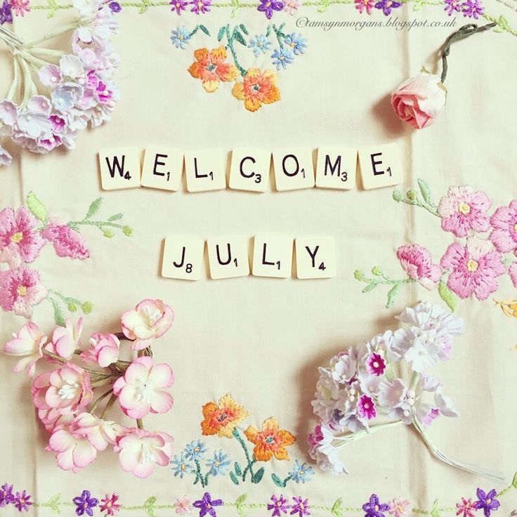 the word welcome is spelled with scrabbles and flowers on a tablecloth