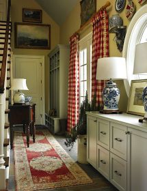 a living room filled with lots of furniture next to a window covered in red and white curtains