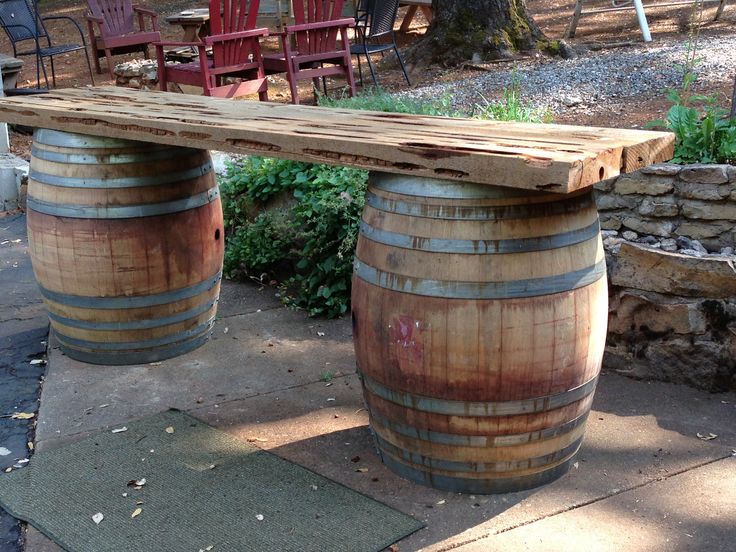 two wooden barrels sitting next to each other on top of a cement floor near chairs