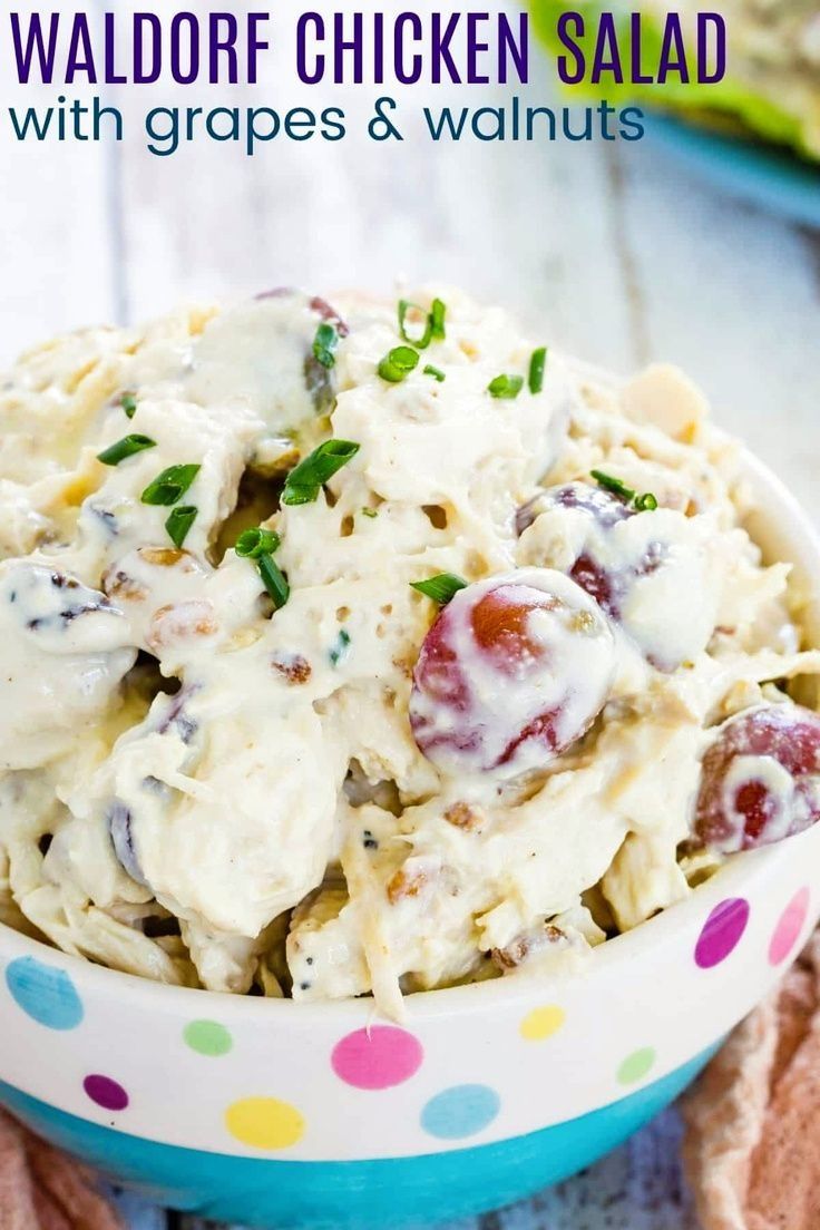 a bowl full of chicken salad with grapes and walnuts in it on top of a table