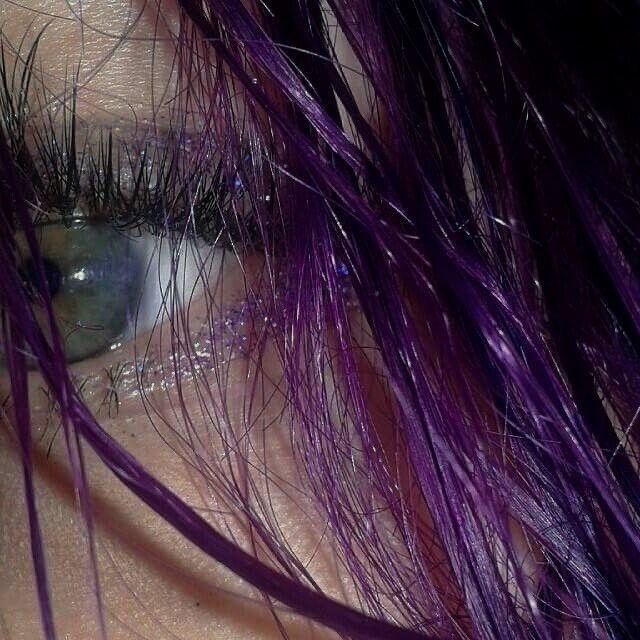 a woman's eye with purple hair and green eyeshade, close up