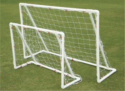 a soccer goal on the grass with red balls in it's back end and bottom corner