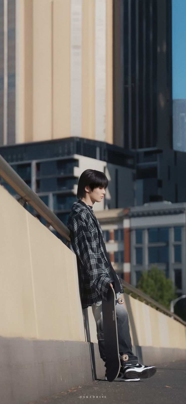 a young man sitting on top of a metal rail with a skateboard in his hand