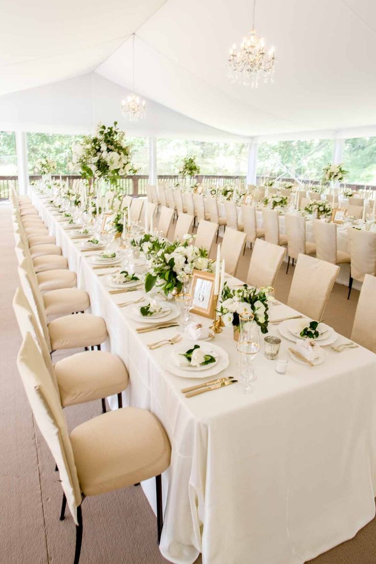 the tables are set with white linens and greenery for an elegant wedding reception