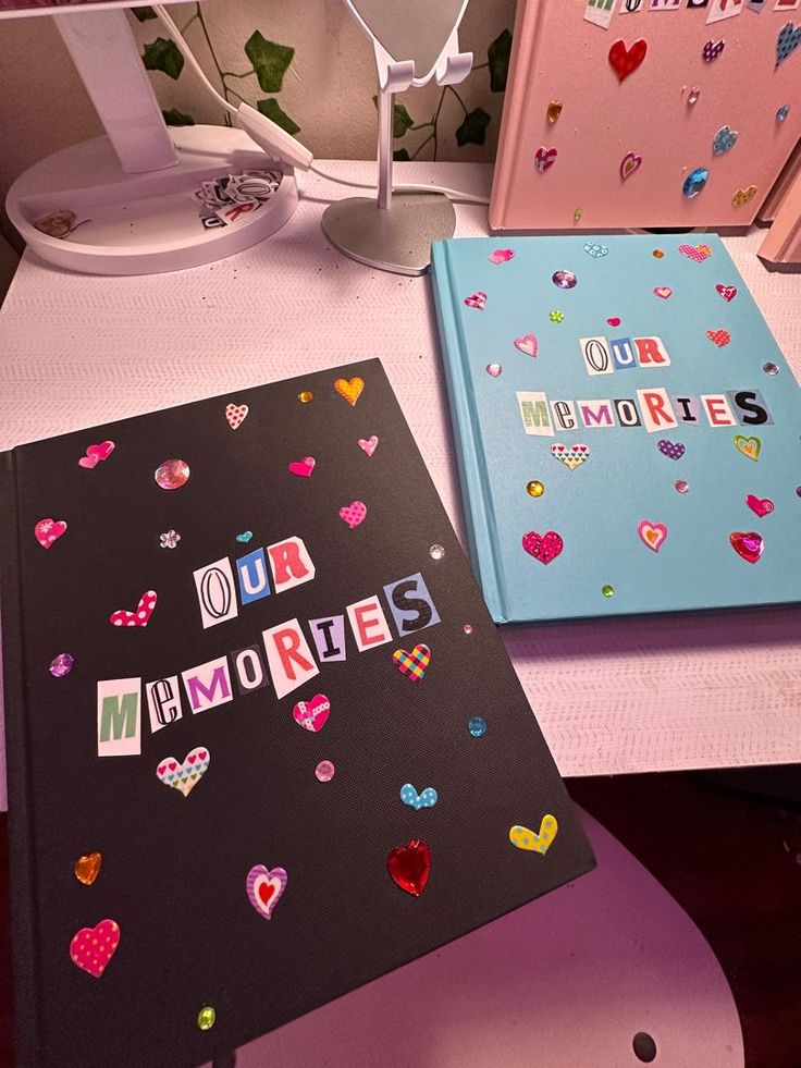 two notebooks sitting next to each other on top of a desk with paper hearts