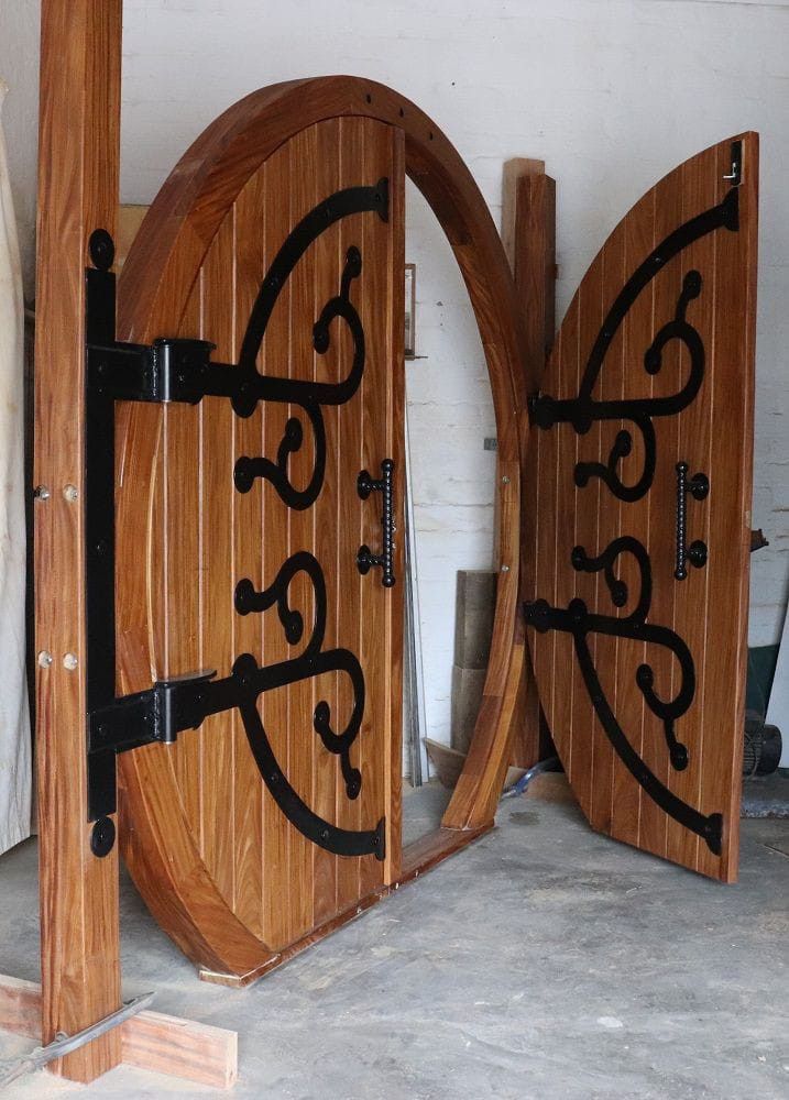 two wooden doors with black iron designs on them in a room next to a wall