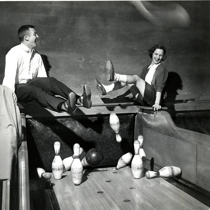 two people sitting on bowling pins with their feet in the air