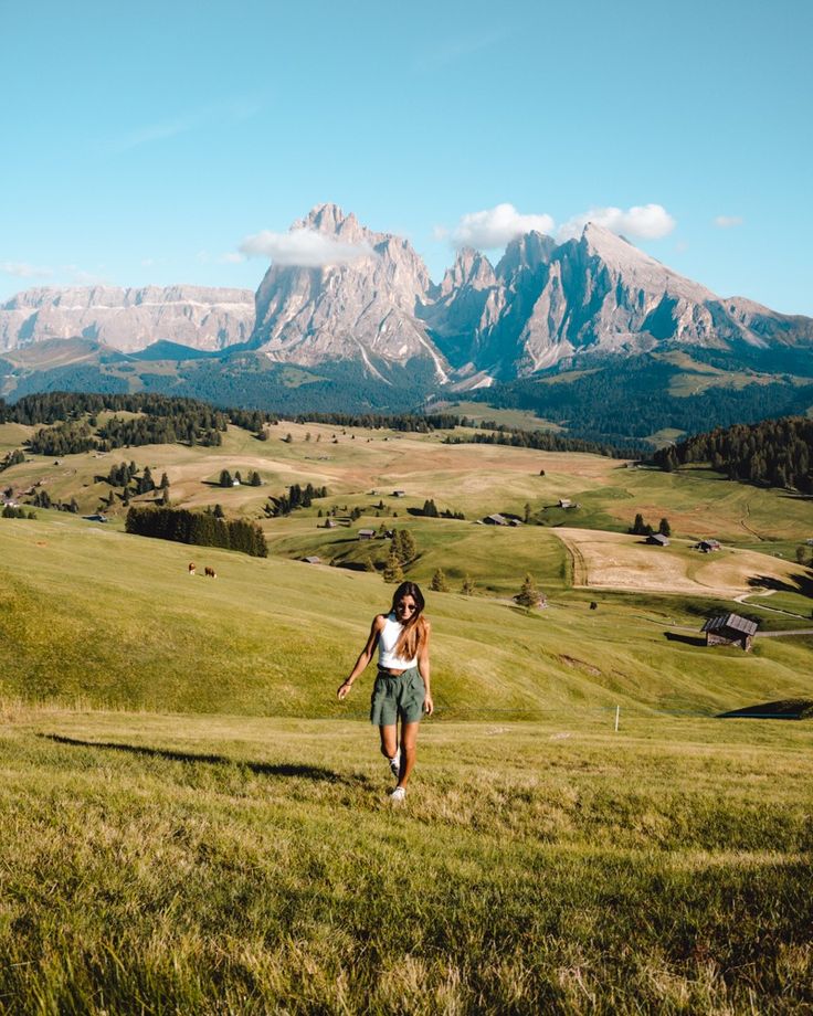 a woman walking across a lush green field