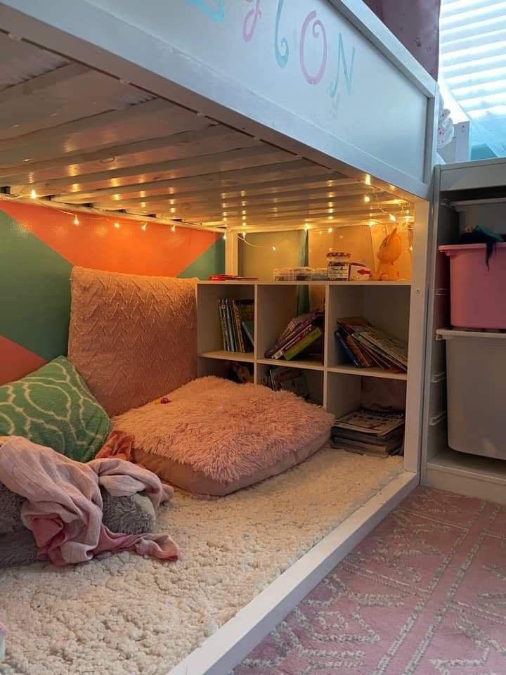 a loft bed with lots of pillows and blankets on it's bottom bunk area