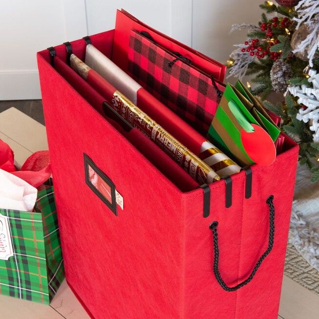 a red shopping bag sitting next to a christmas tree