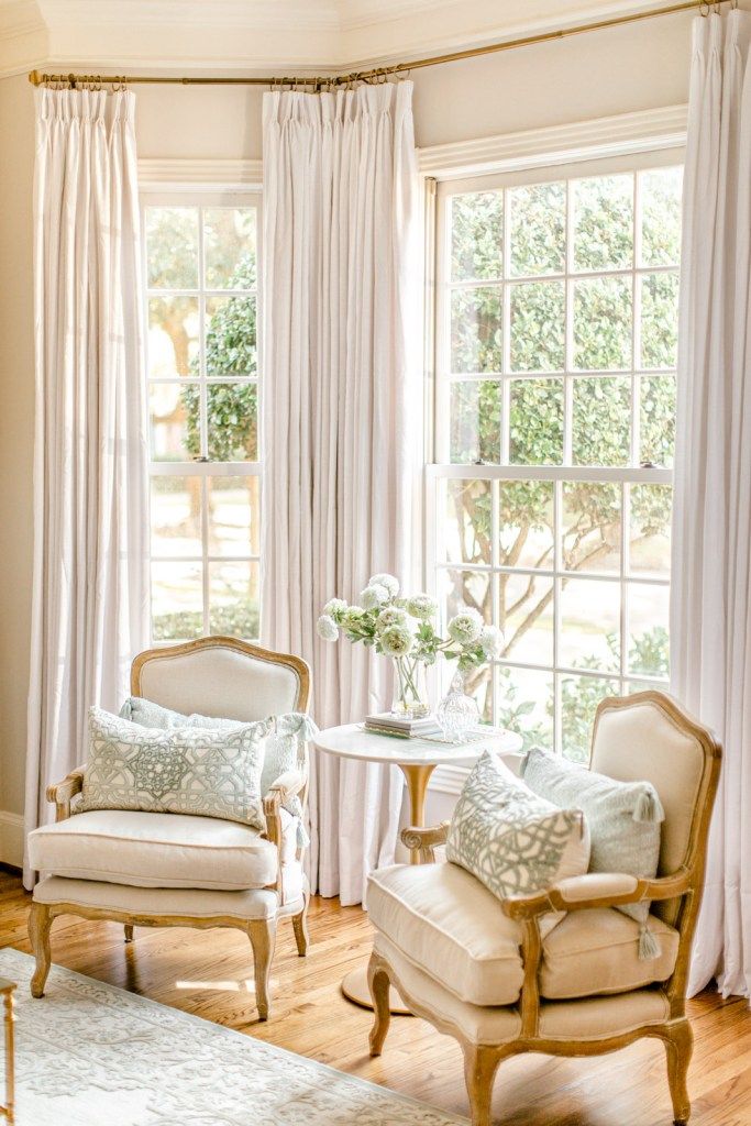 a living room filled with furniture and windows covered in white draping next to a wooden floor