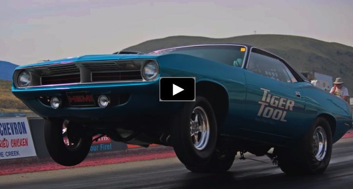 a blue muscle car driving down a race track