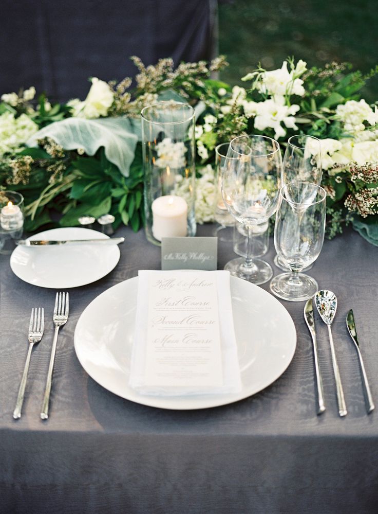 the table is set with white flowers and silverware