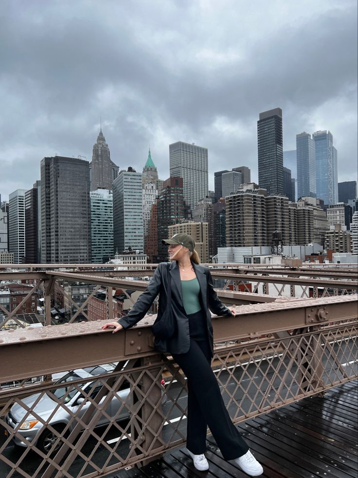 a woman standing on top of a bridge in front of the cityscape with skyscrapers