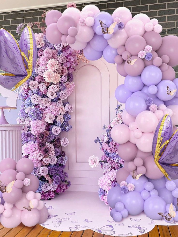 the balloon arch is decorated with flowers and butterflies