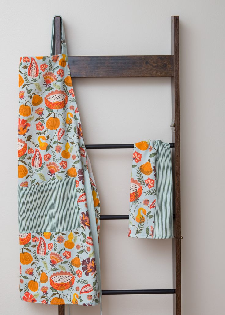 two towels hanging on a towel rack next to an old ladder