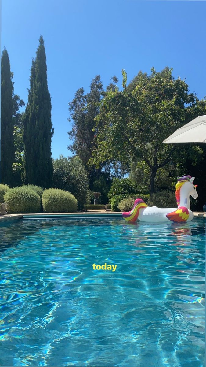 an inflatable unicorn float floating on top of a swimming pool next to trees