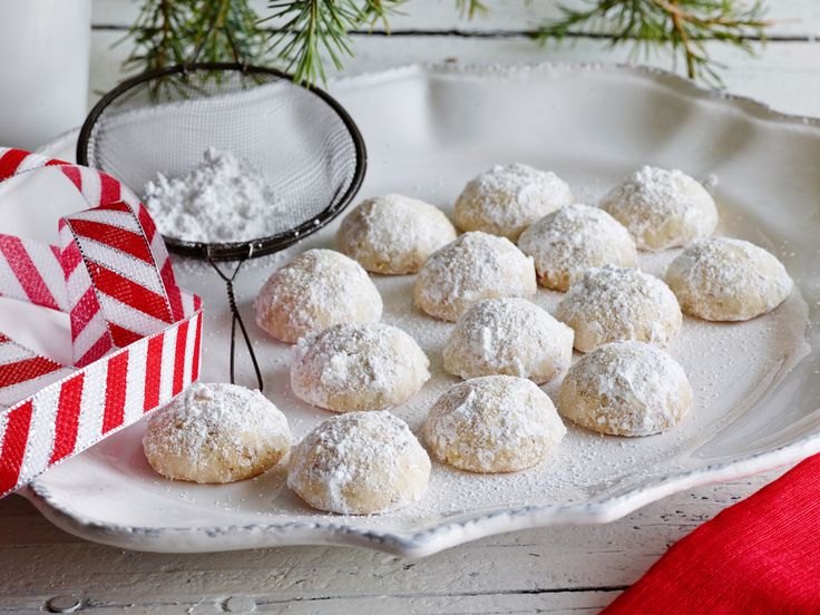 powdered sugar covered cookies on a plate next to a christmas present