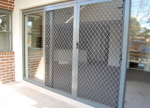 an open glass door on the side of a building with a brick wall behind it