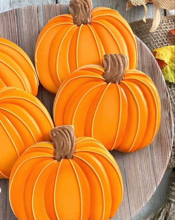 pumpkin shaped cookies sitting on top of a wooden plate