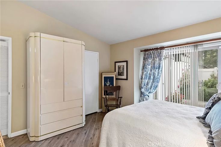 a bedroom with a bed, dresser and sliding glass doors